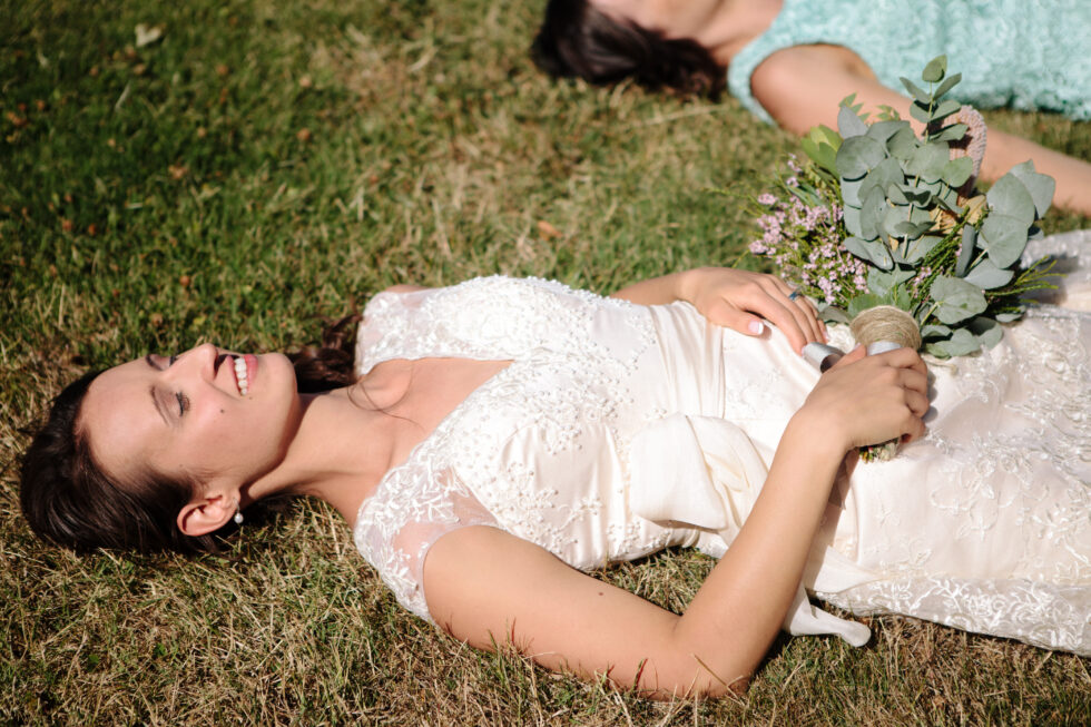 The bride lay down in the grass with her bouquet.